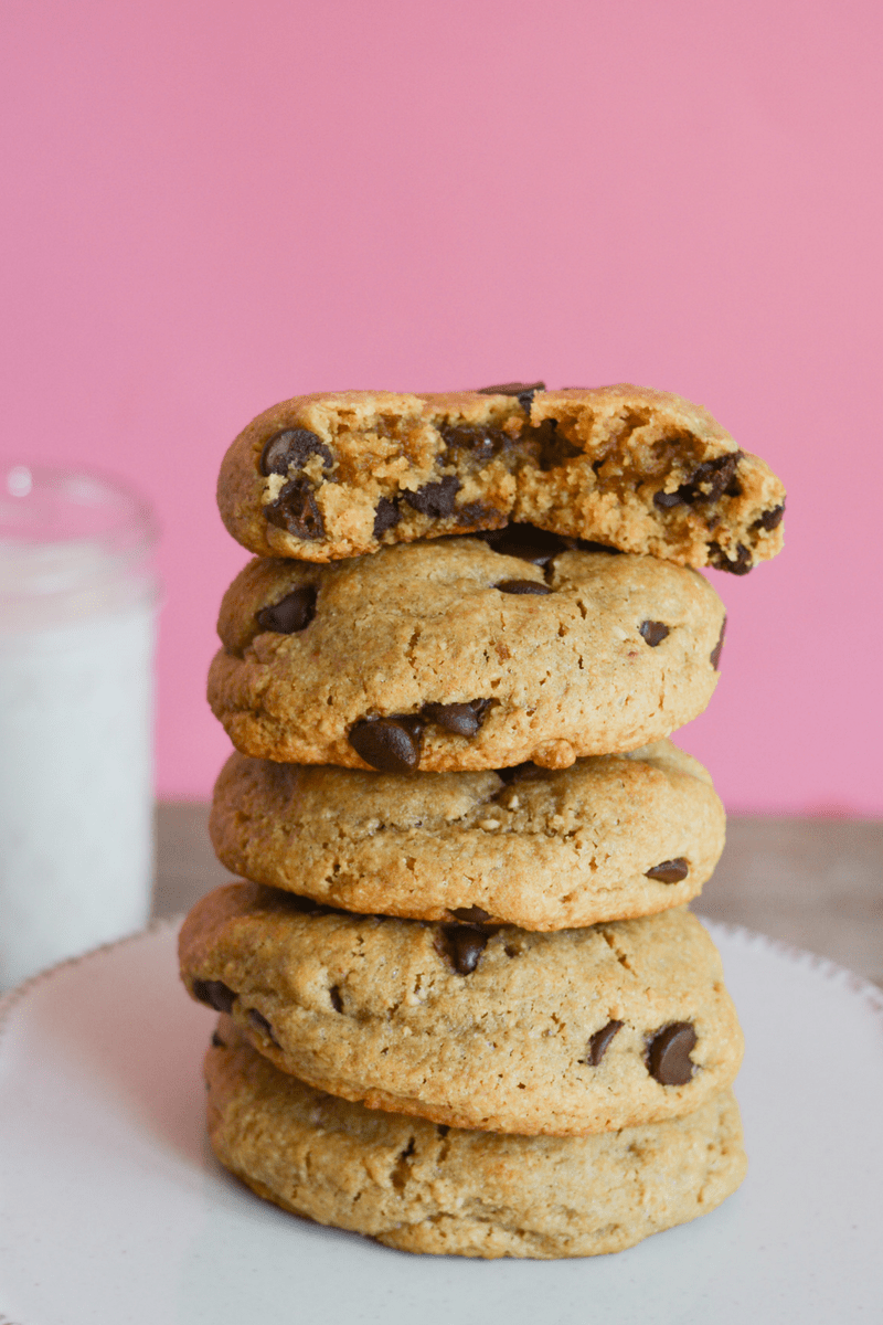 stack of keto chocolate chip cookies on a white base with a pink background 