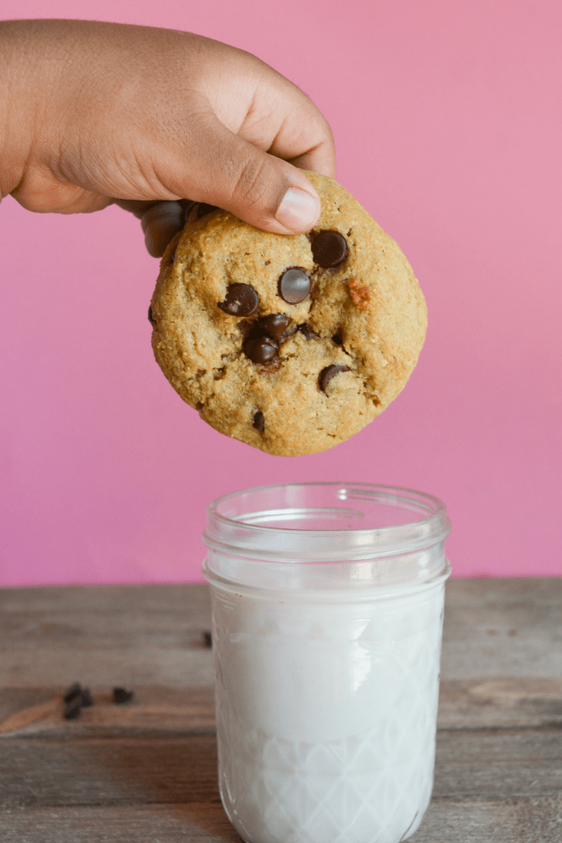 keto cookie being held over a small glass of almond milk