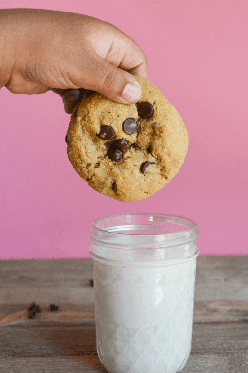 keto cookie being held over a small glass of almond milk