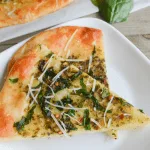 two slices of keto spinach pesto flatbread on a white plate