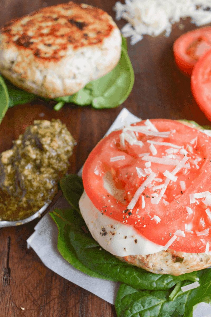 fully dressed chicken pesto burger next to spoon of pesto