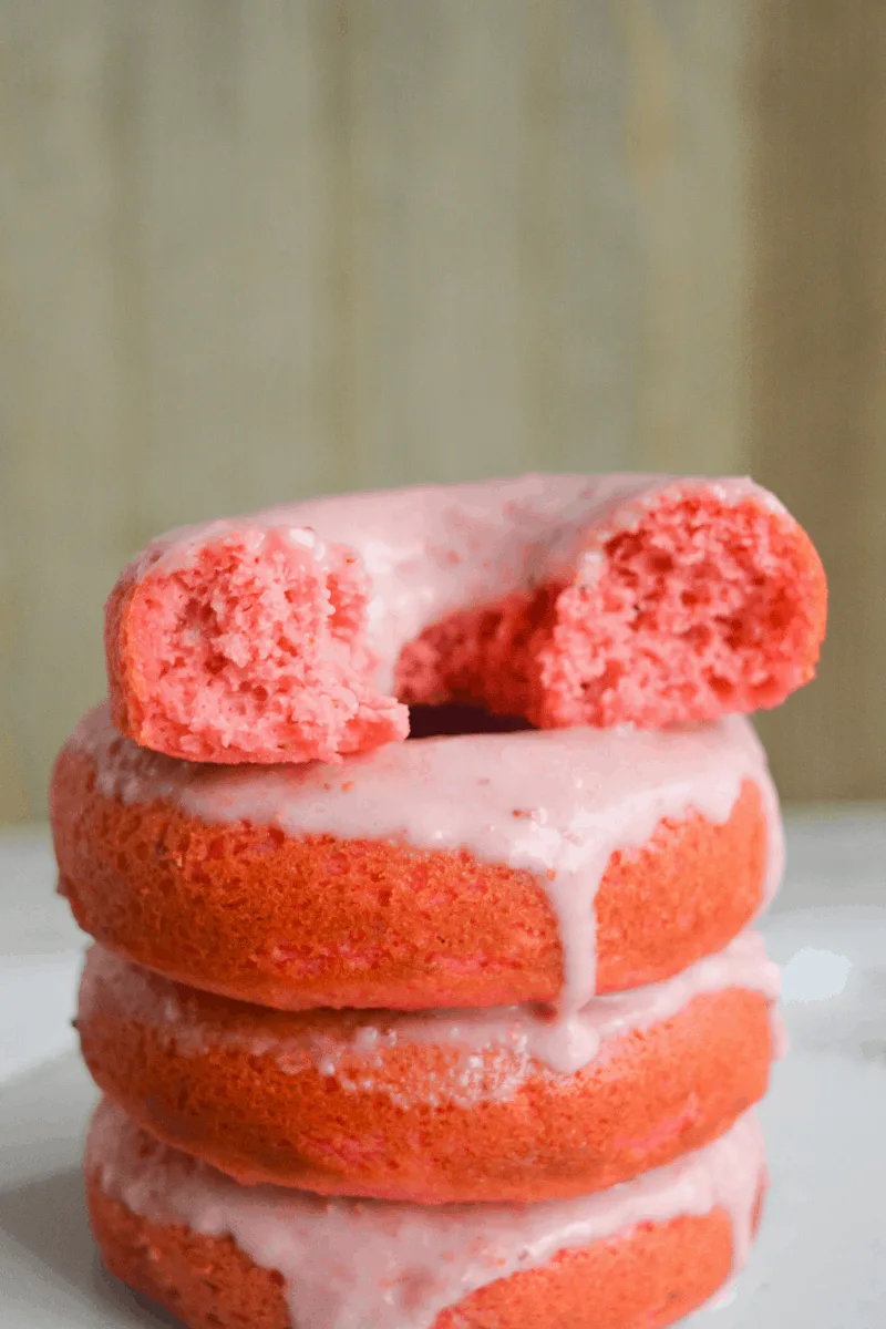 four stacked glazed keto strawberry donuts