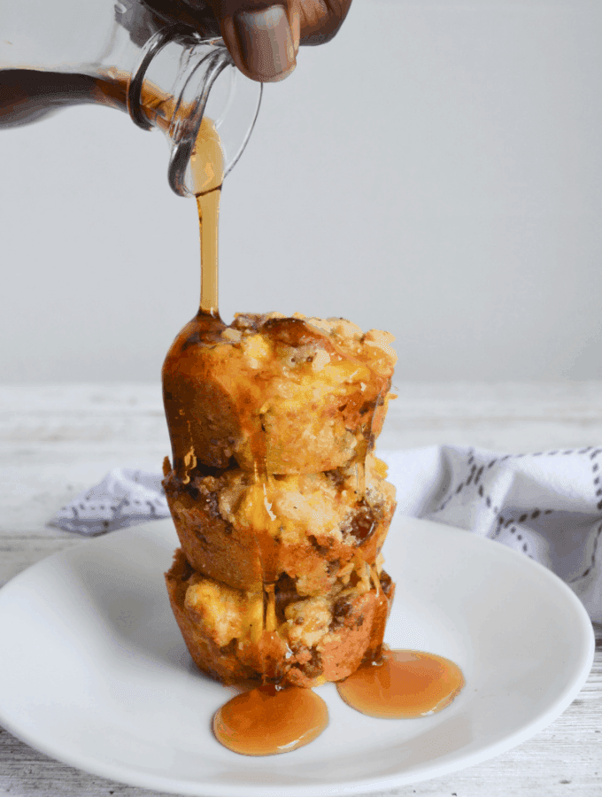 three stacked keto breakfast bombs on a white plate with syrup being poured over them