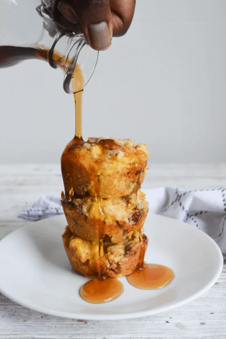 three stacked keto breakfast bombs on a white plate with syrup being poured over them