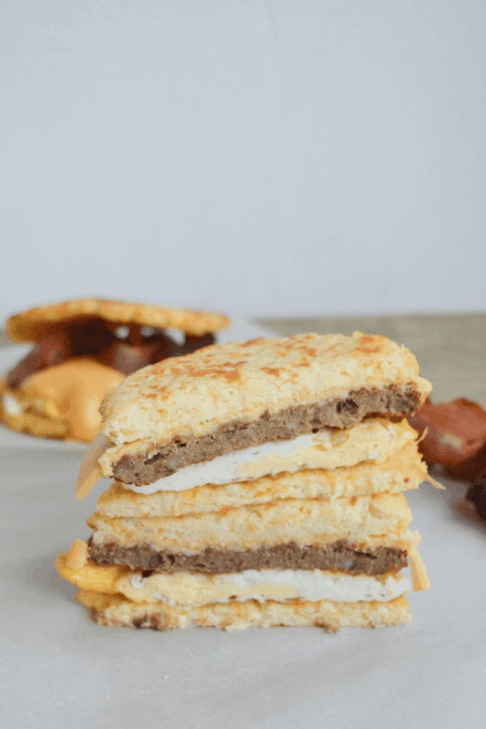 breakfast sandwiched sliced in half to show the texture of cauliflower buns