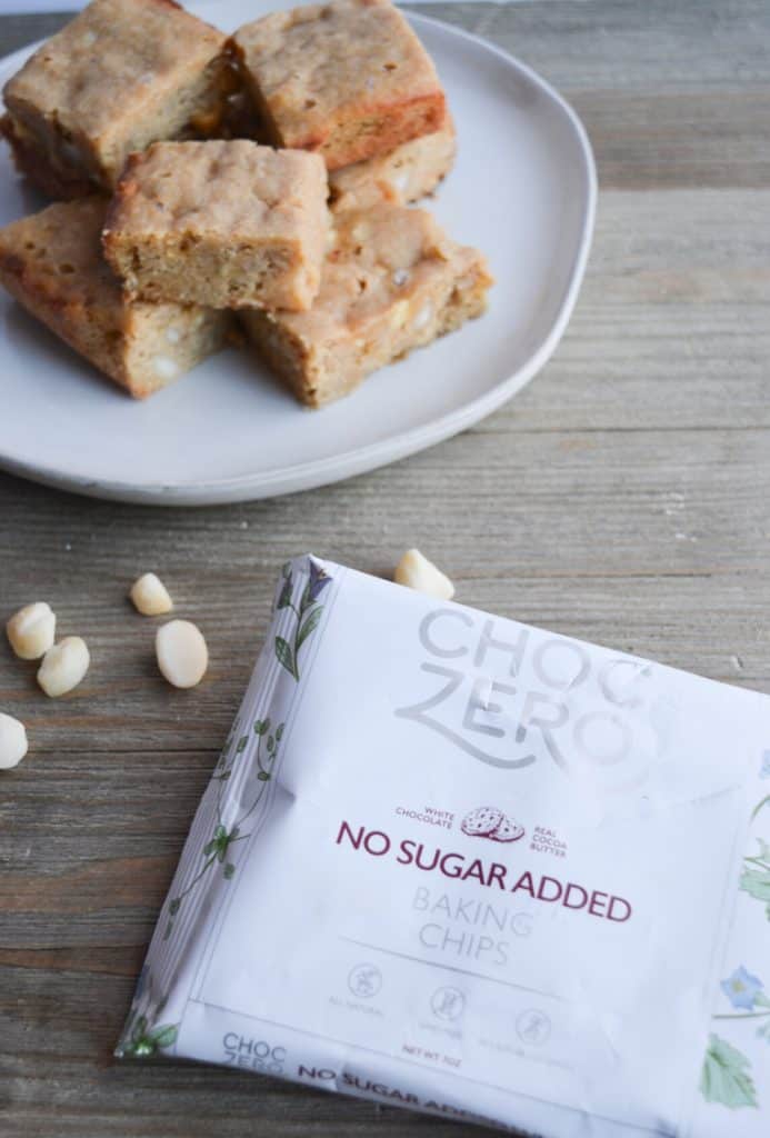 stack of blondies in the background with package of choczero white chocolate chips in the foreground