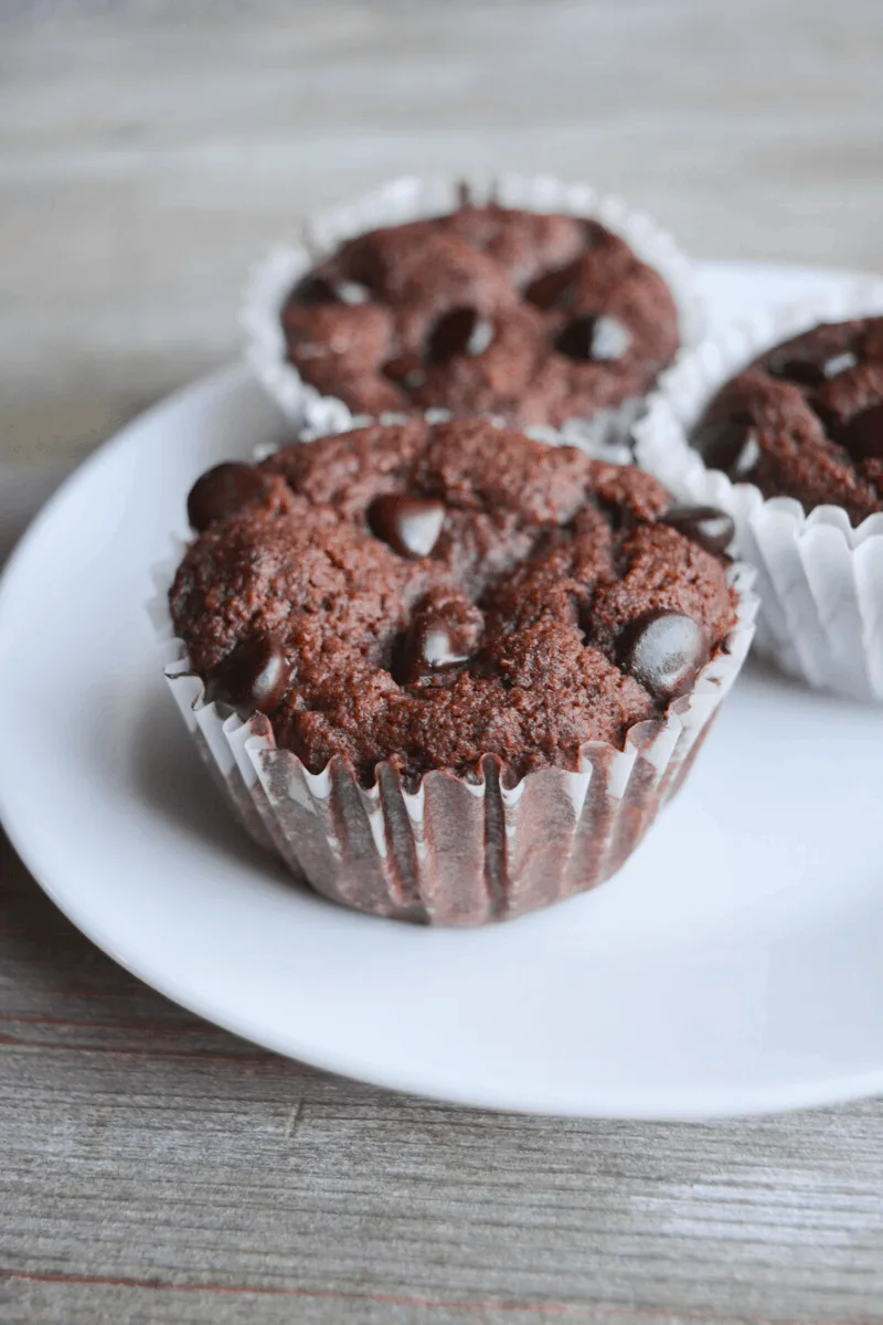 three keto double chocolate muffins sitting on a white plate