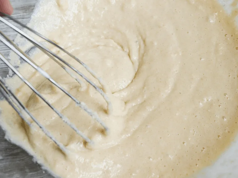 dry and wet ingredients being whisked in a mixing bowl 