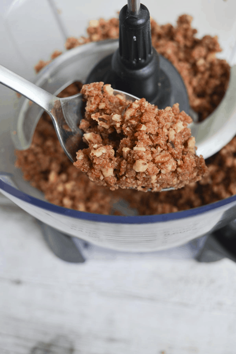 a spoonful of crumble topping taken out of the food processor to show the crumbly texture you want to achieve