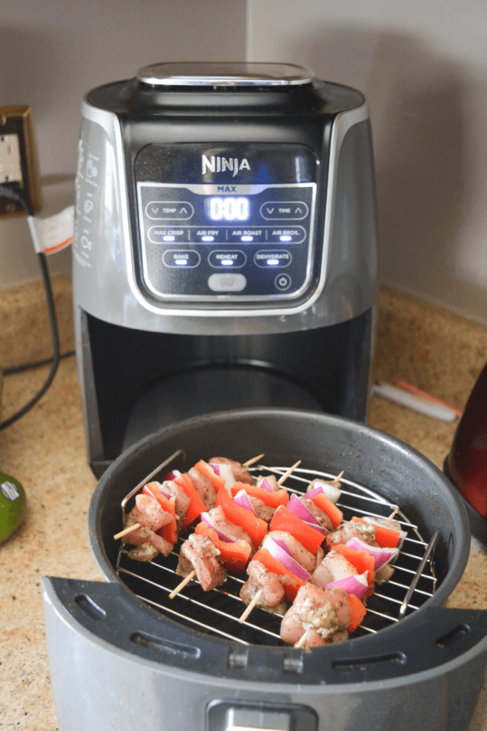 uncooked jerk chicken kebabs sitting on a rack inside of an air fryer basket