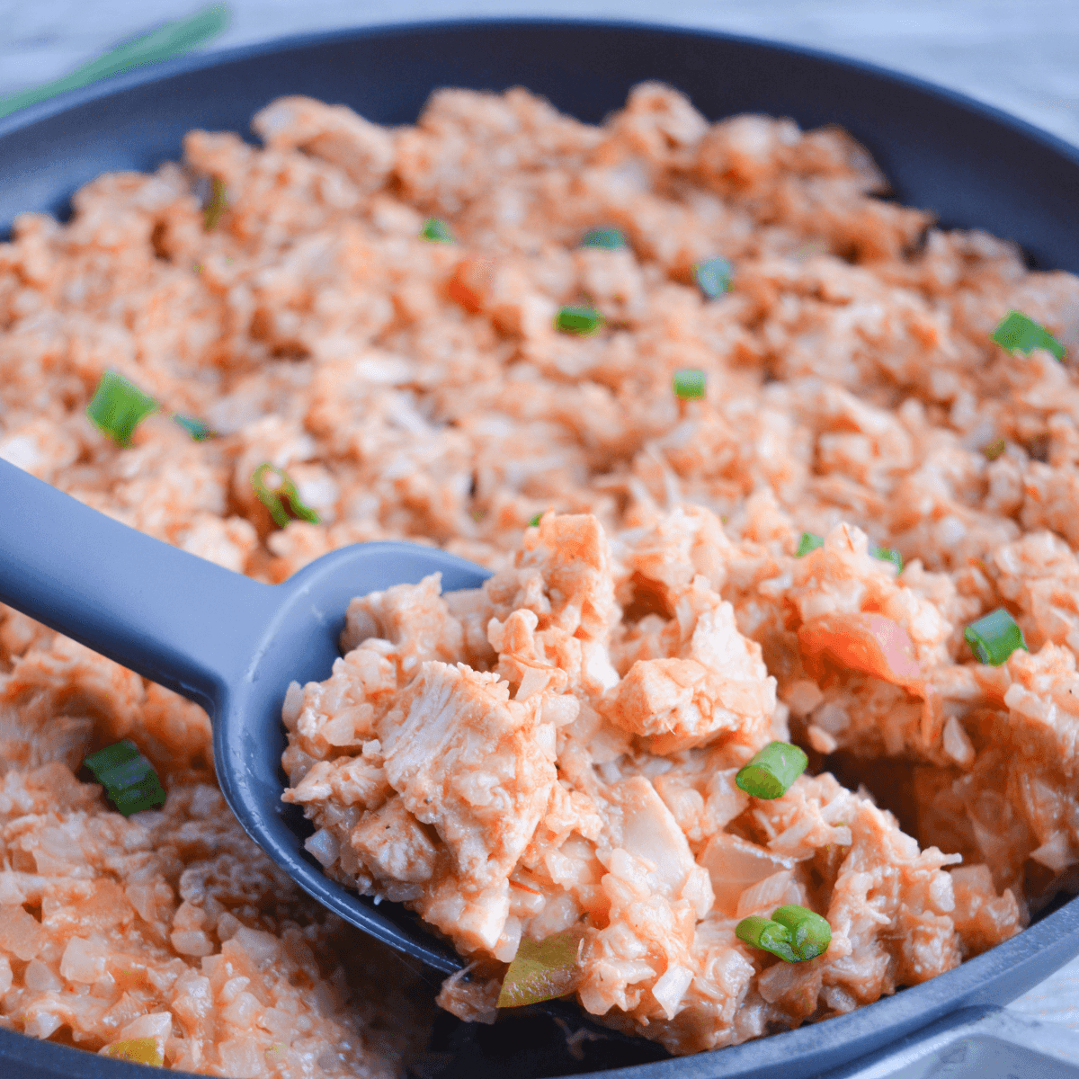 close of of keto chicken skillet with cheese, salsa, cauliflower rice, and green onions