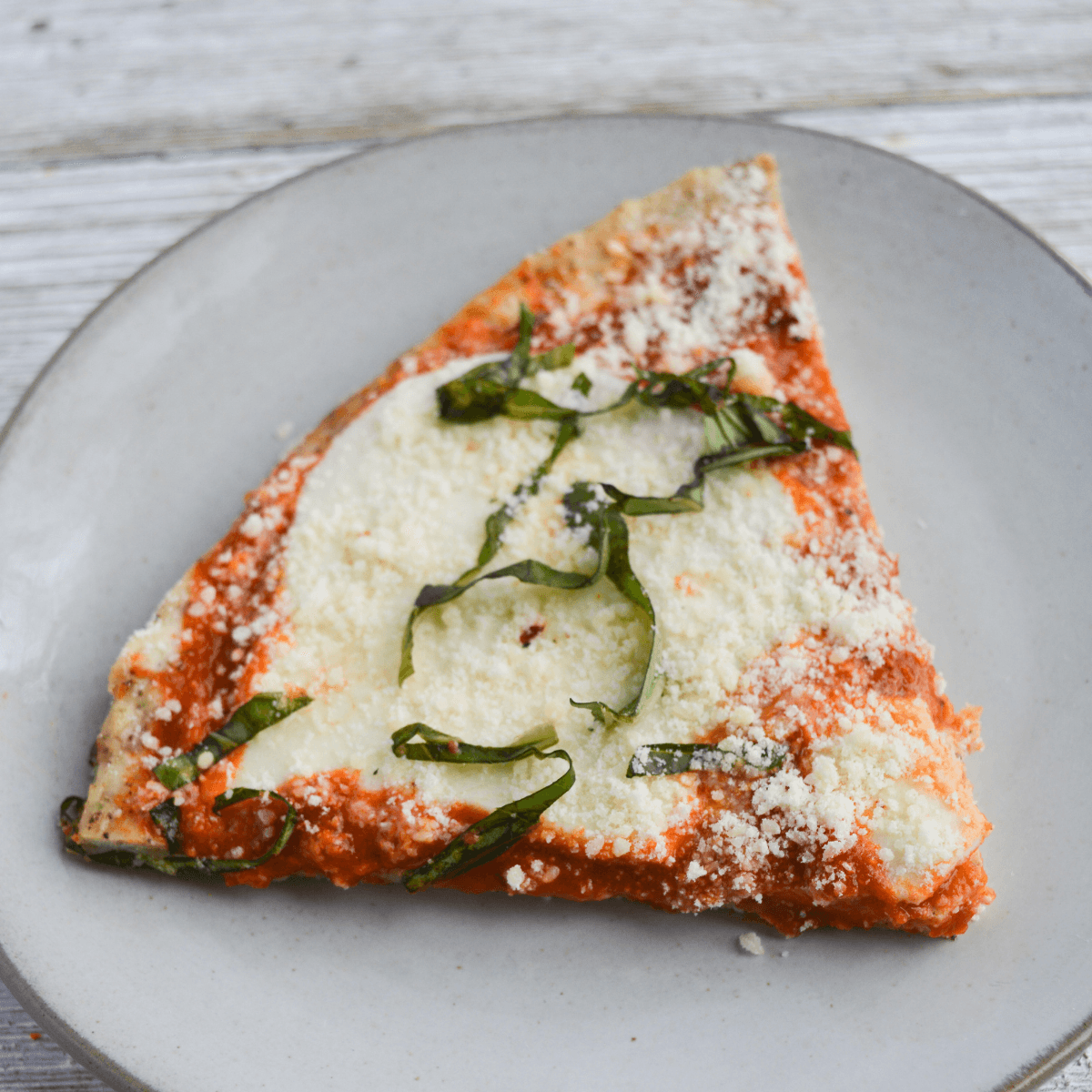 one slice of keto chicken crust pizza on a white plate