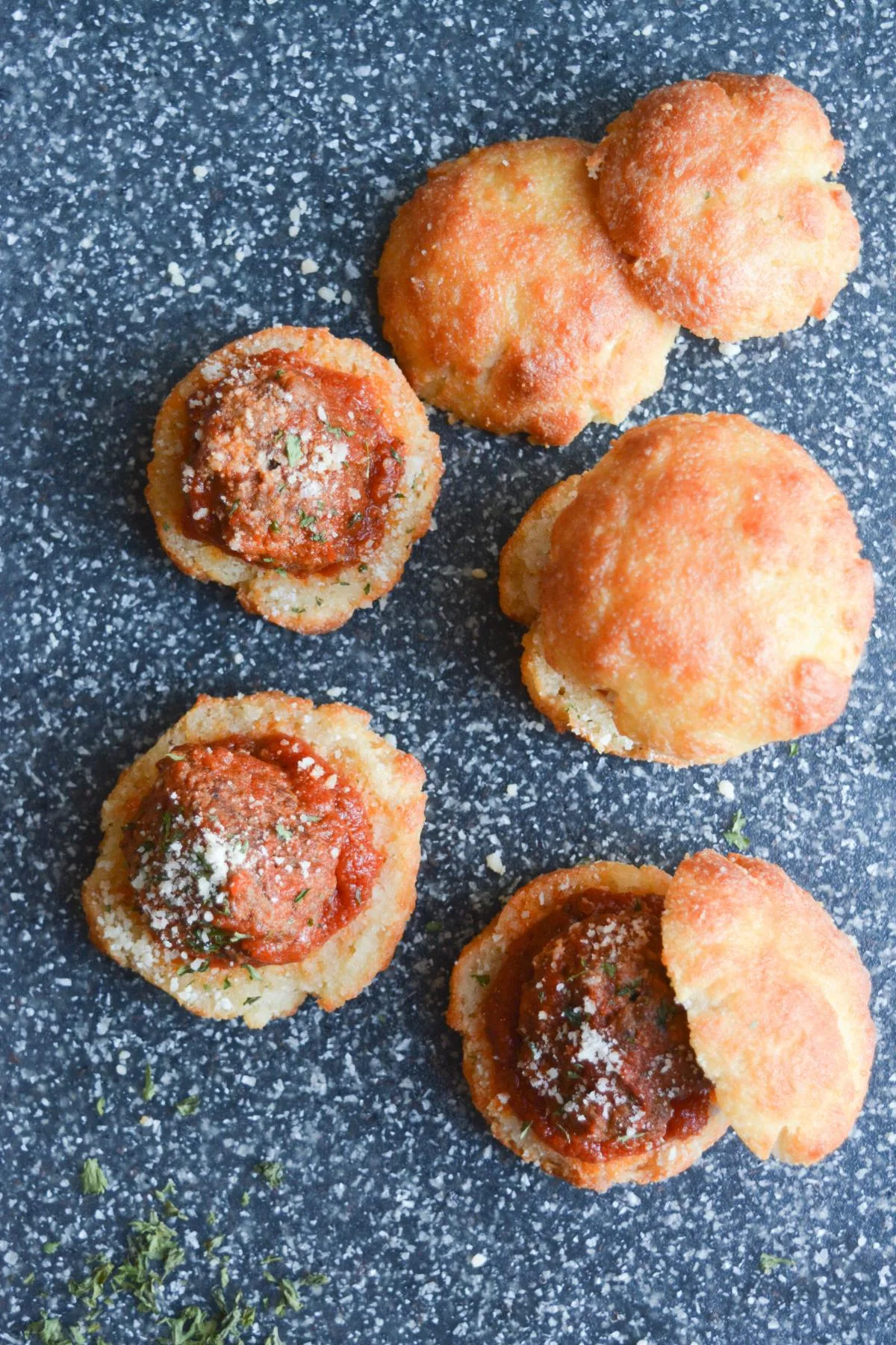 overhead shot of several garlic bread meatball sliders, showing the seasoned meatballs covered in parmesan cheese