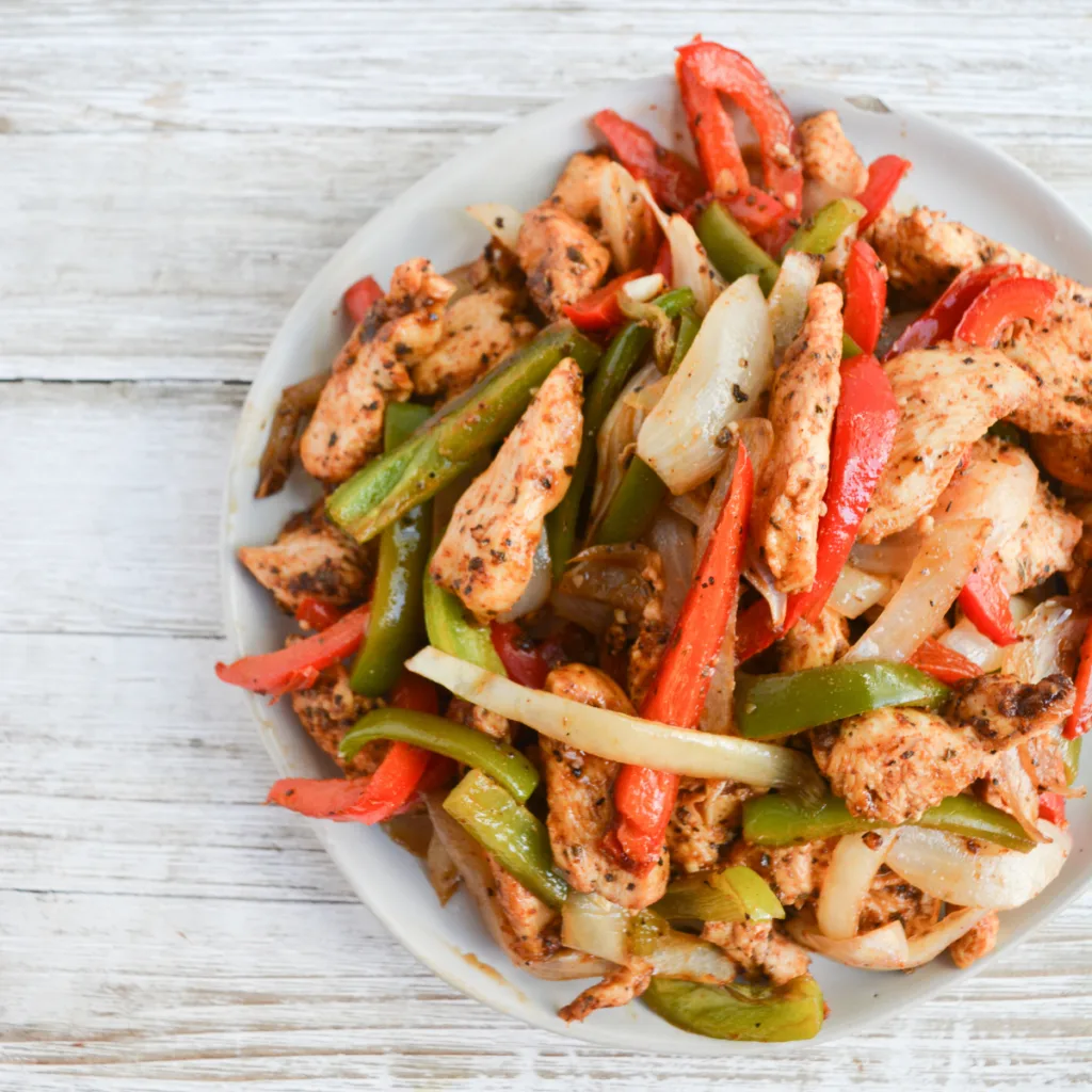 close up on a heaping plate of sheet pan chicken fajitas.
