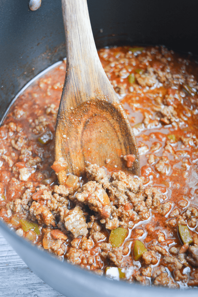 a wooden spoon stirring a pot of keto chili