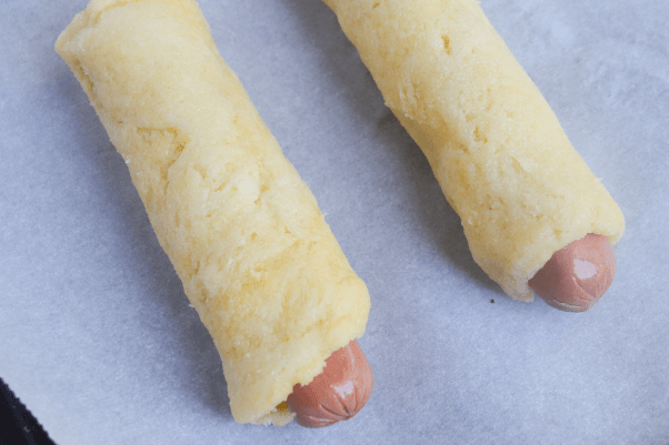 keto pigs in a blanket step 3 - wrapping the hot dogs with fathead dough