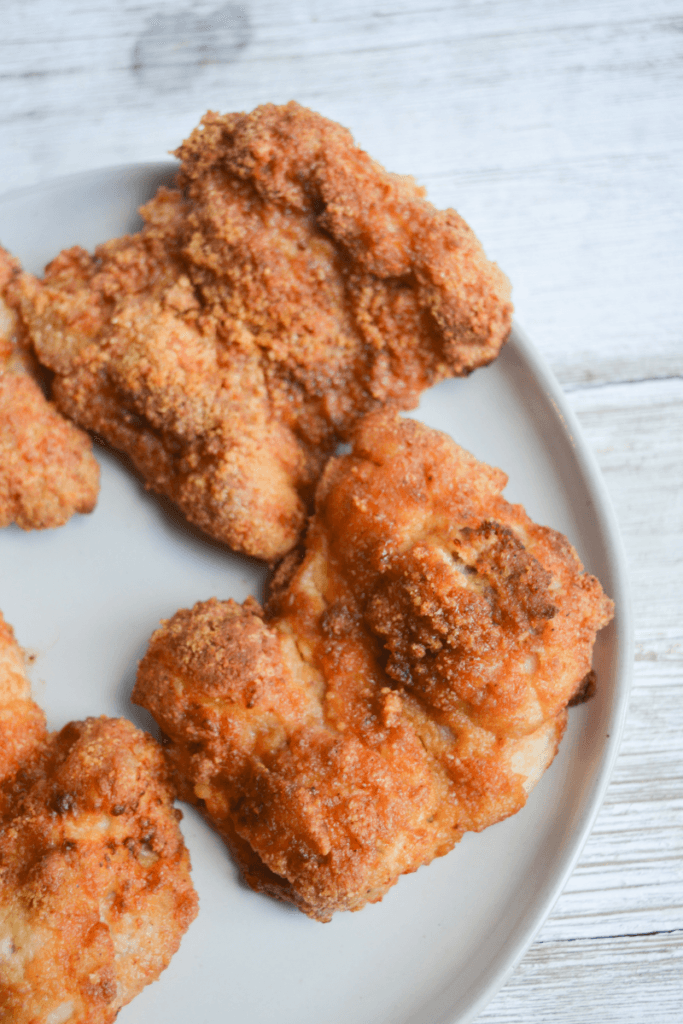 pieces of crispy low carb air fryer keto fried chicken thighs on a white plate