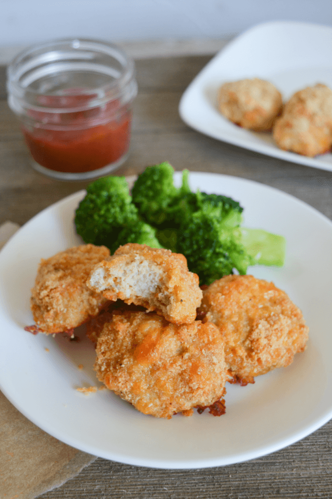 plate of keto chicken nuggets and broccoli with a bite taken out of one of the nuggets