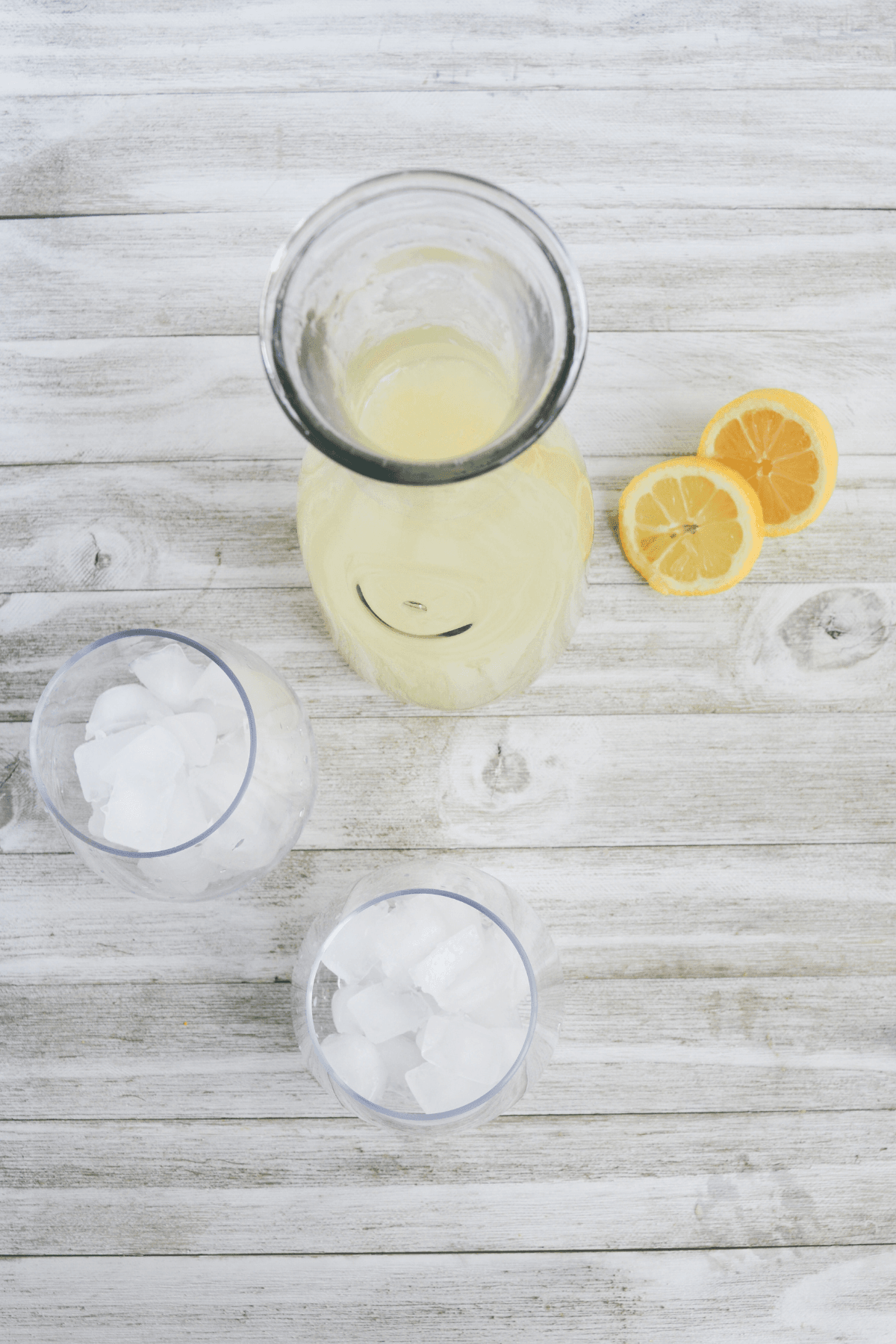 carafe full of low carb lemonade, with two glasses full of ice and a sliced lemon