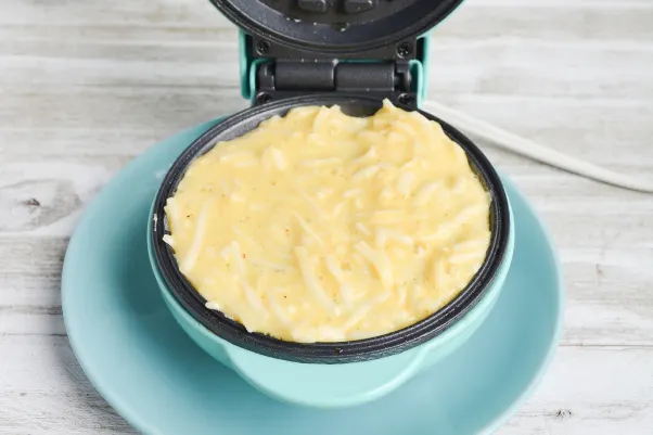 close up on chaffles mixture on an open waffle iron