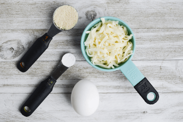 ingredients for making chaffles: shredded mozzarella cheese, almond flour, baking powder, and egg