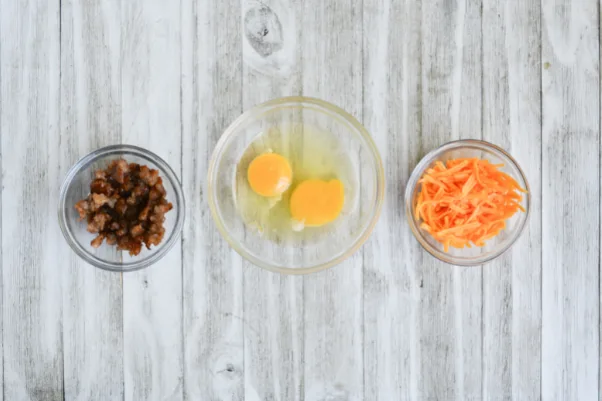 three bowls, containing breakfast sausage, eggs, and shredded cheddar cheese, respectively