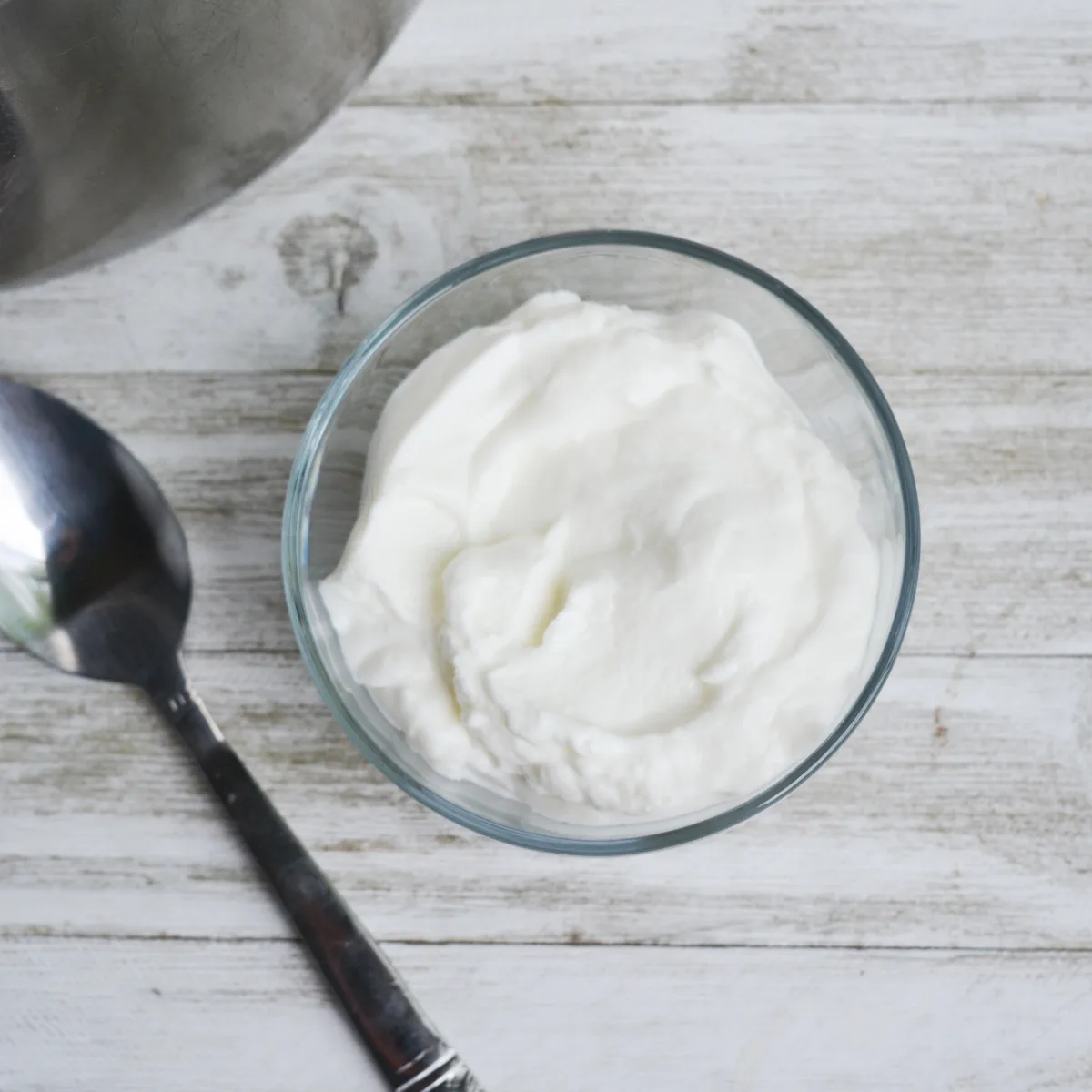 serving of instant pot yogurt in a small bowl beside a spoon