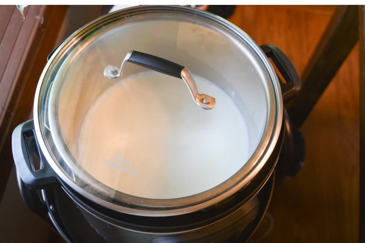 Le yaourt céto incubé avec un couvercle en verre sur le dessus de la marmite instantanée.