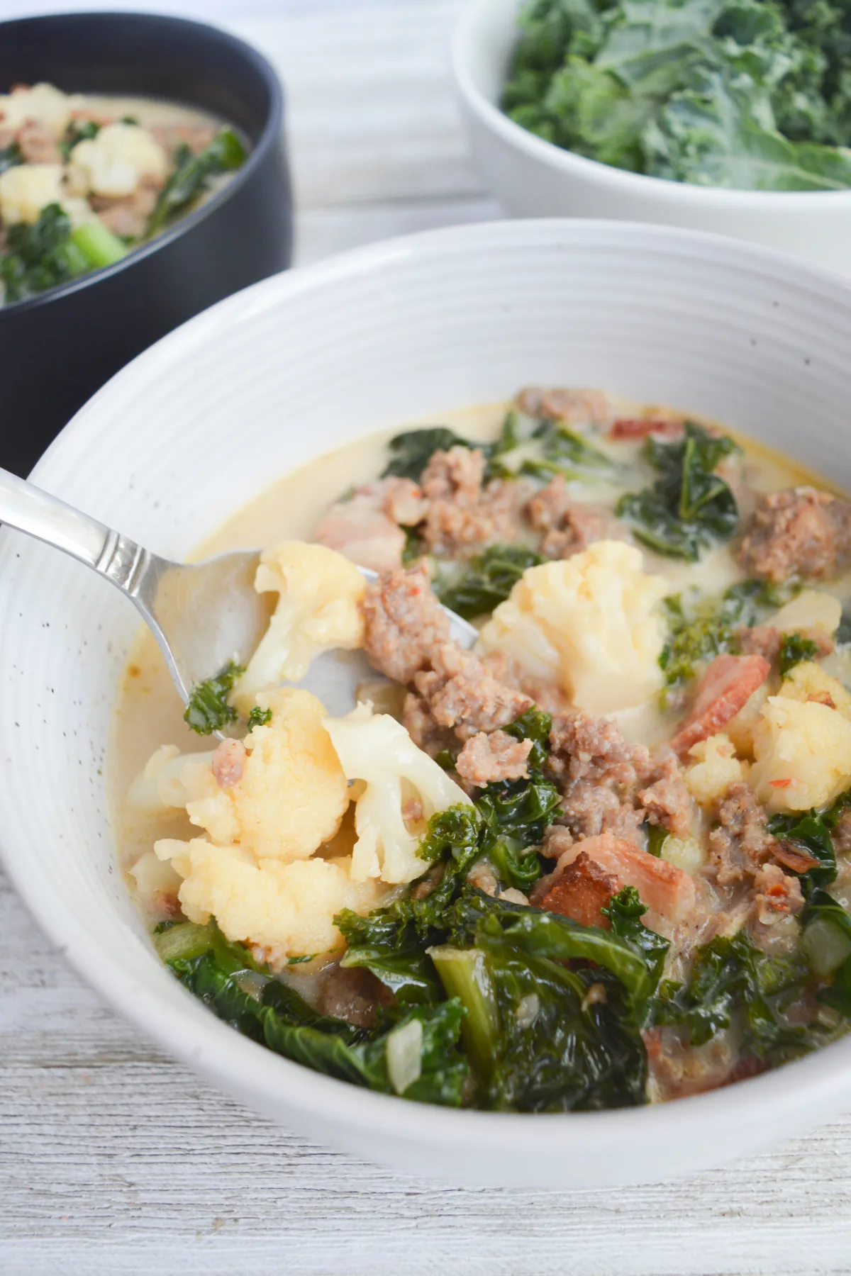 close up of keto zuppa toscana soup with a spoon in the bowl.