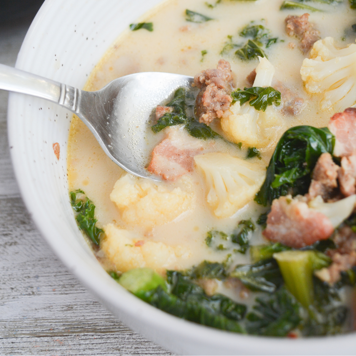 closeup of keto zuppa toscana in a white bowl with a spoon.